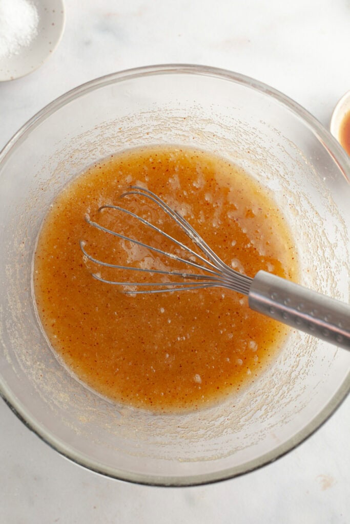 Browned butter and sugar mixed together in a glass bowl with a whisk.