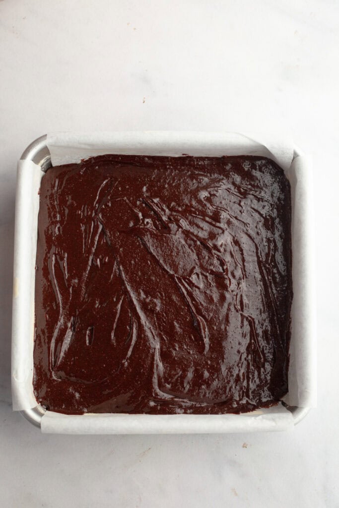Unbaked brownies in a square pan.
