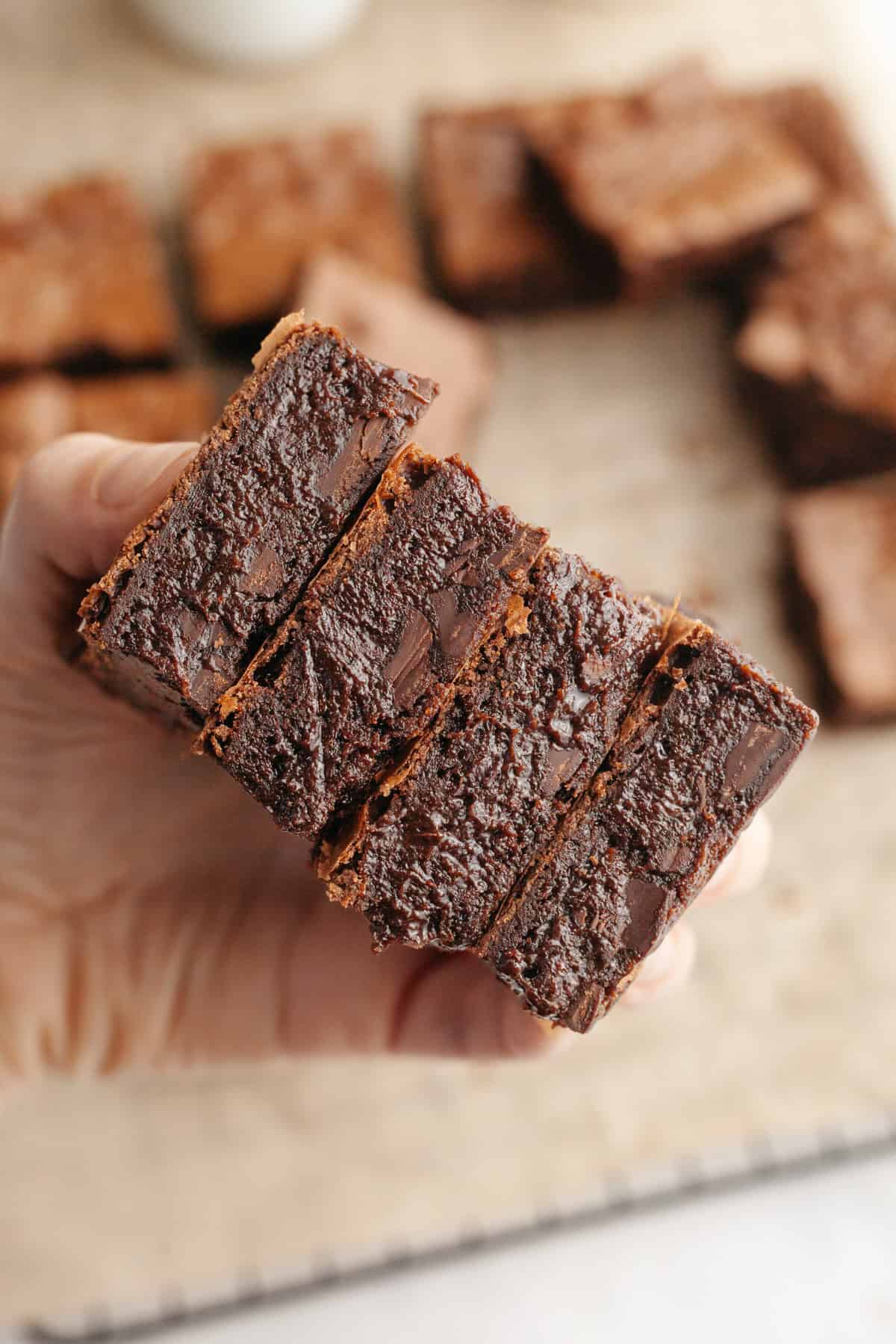 A hand holding 4 espresso brown butter fudgy brownies.