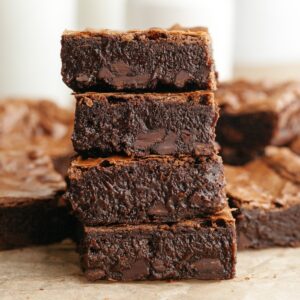 A stack of four brown butter espresso brownies on parchment paper.