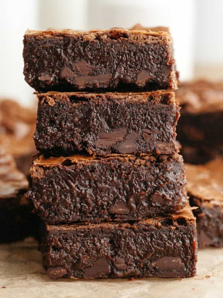 A stack of four brown butter espresso brownies on parchment paper.