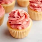 Vanilla cupcakes topped with pink raspberry frosting.