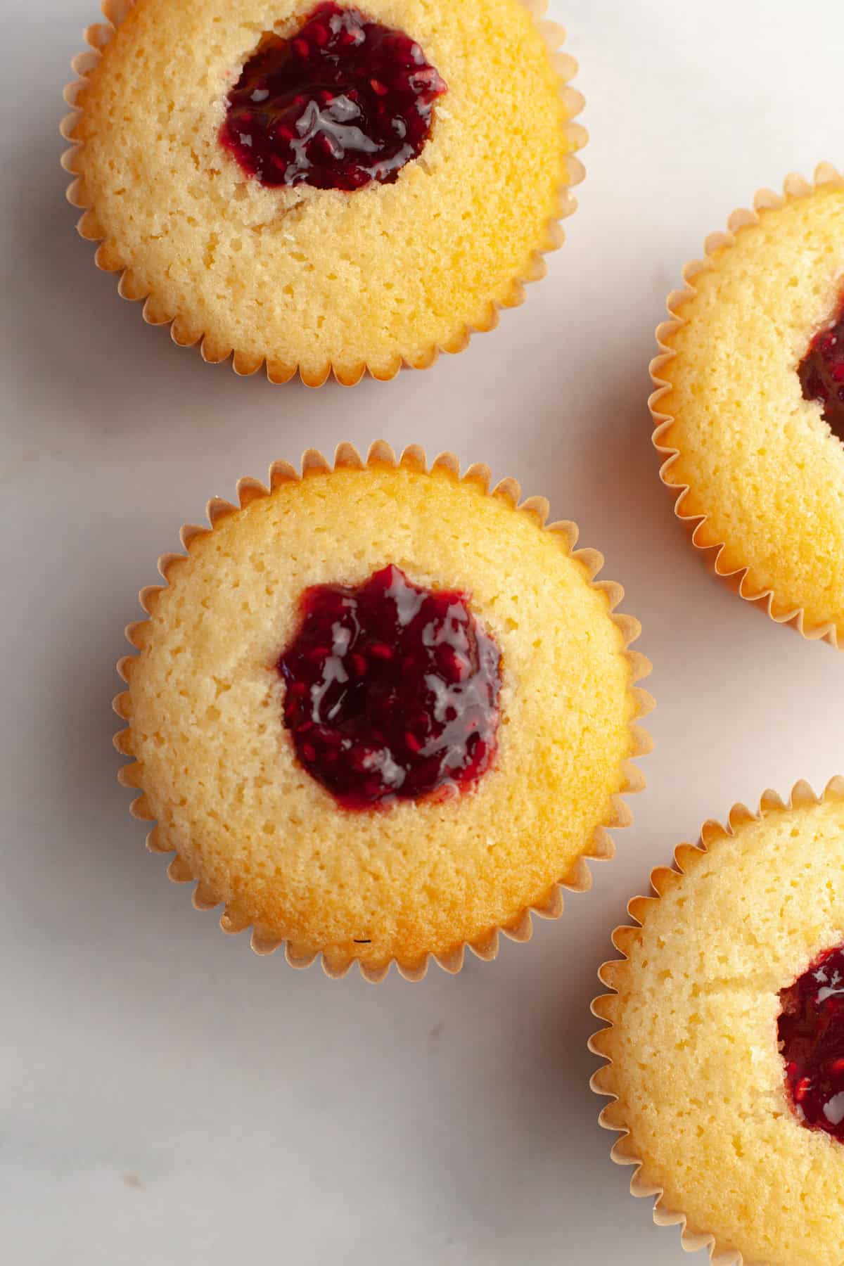 Almond cupcakes cored and filled with raspberry jam.