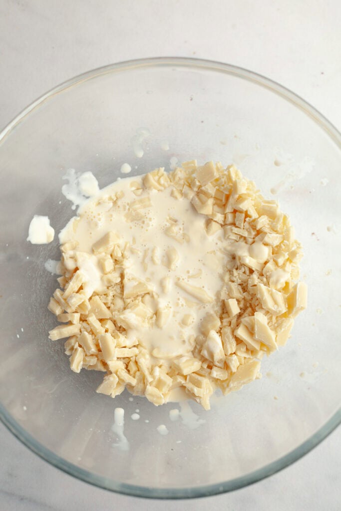 A bowl with chopped white chocolate and heavy cream poured on top of it.