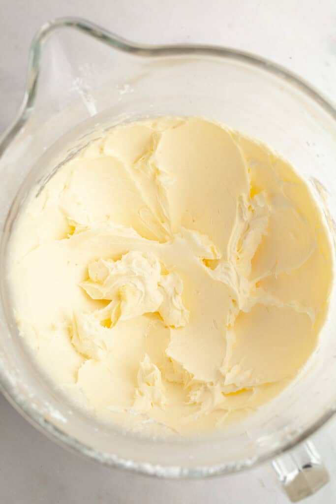Butter and icing sugar mixed in a large glass mixing bowl.