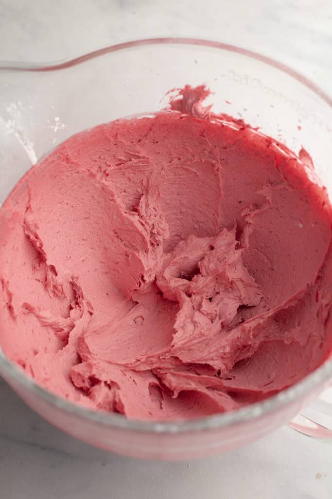 Pink frosting in a large glass bowl.