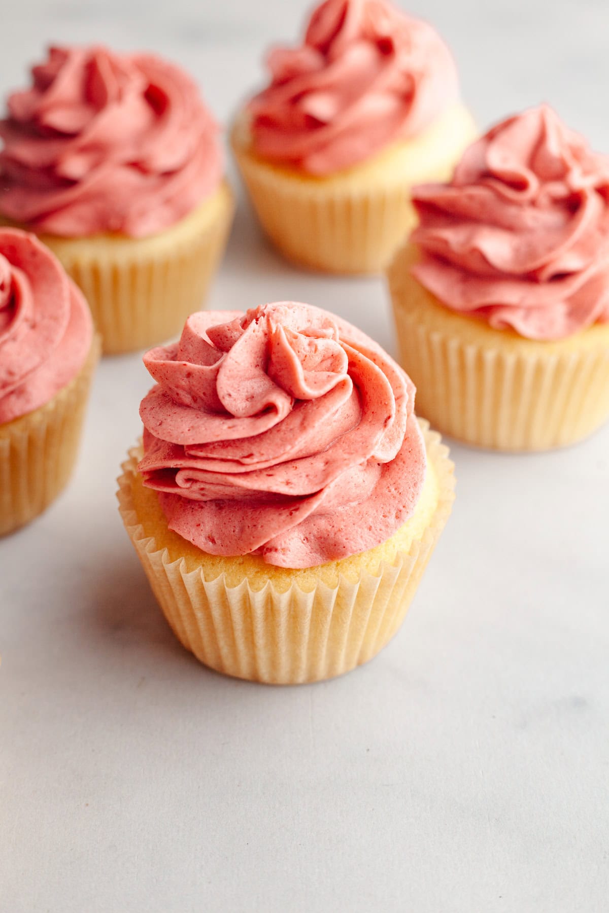 Vanilla cupcakes topped with pink raspberry frosting.