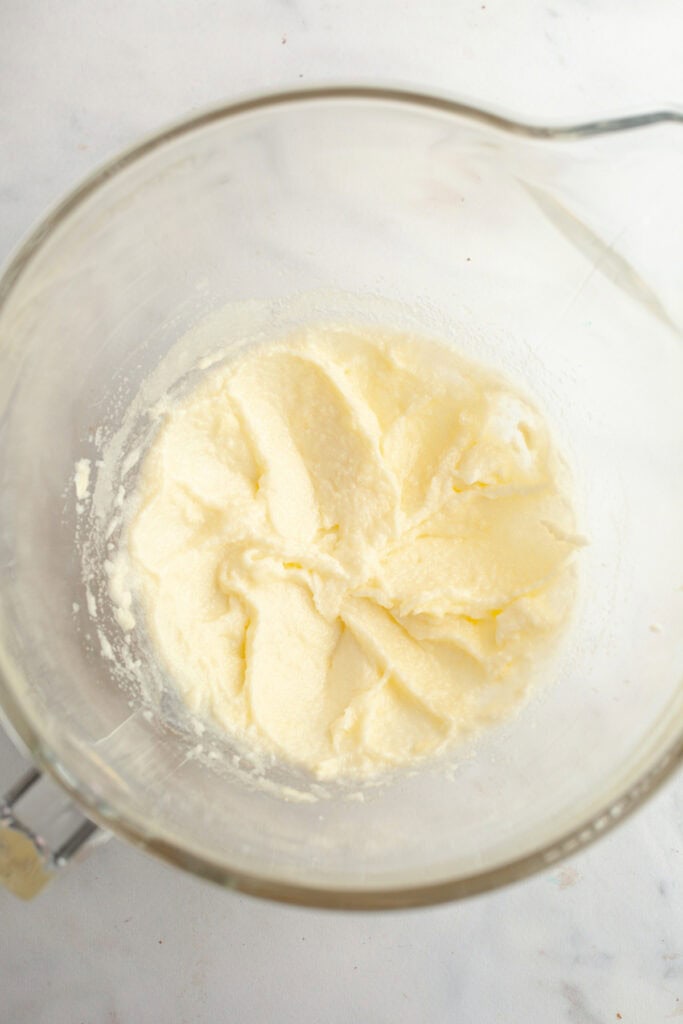 A large glass mixing bowl with creamed butter and sugar in it.