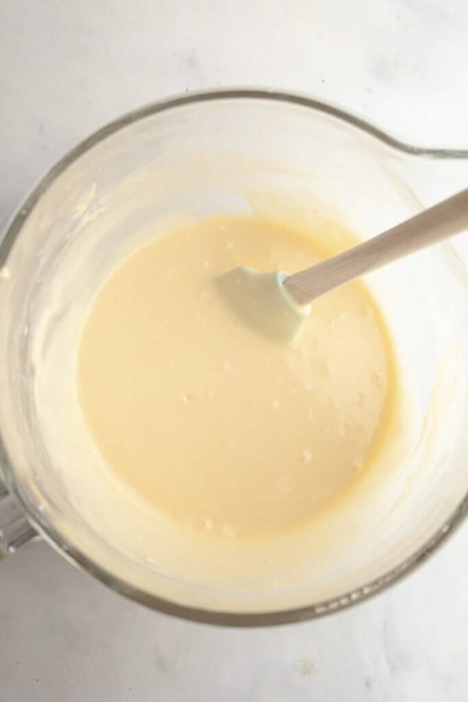 A large glass mixing bowl with vanilla cupcake batter.