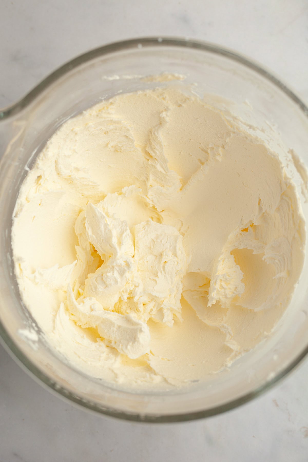 Pale yellow American buttercream in a glass bowl.