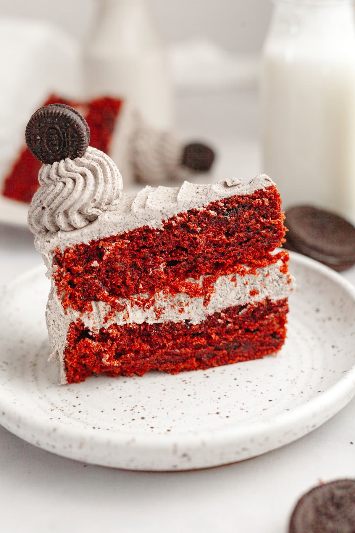 A slice of red velvet cake with Oreo frosting on a small plate.
