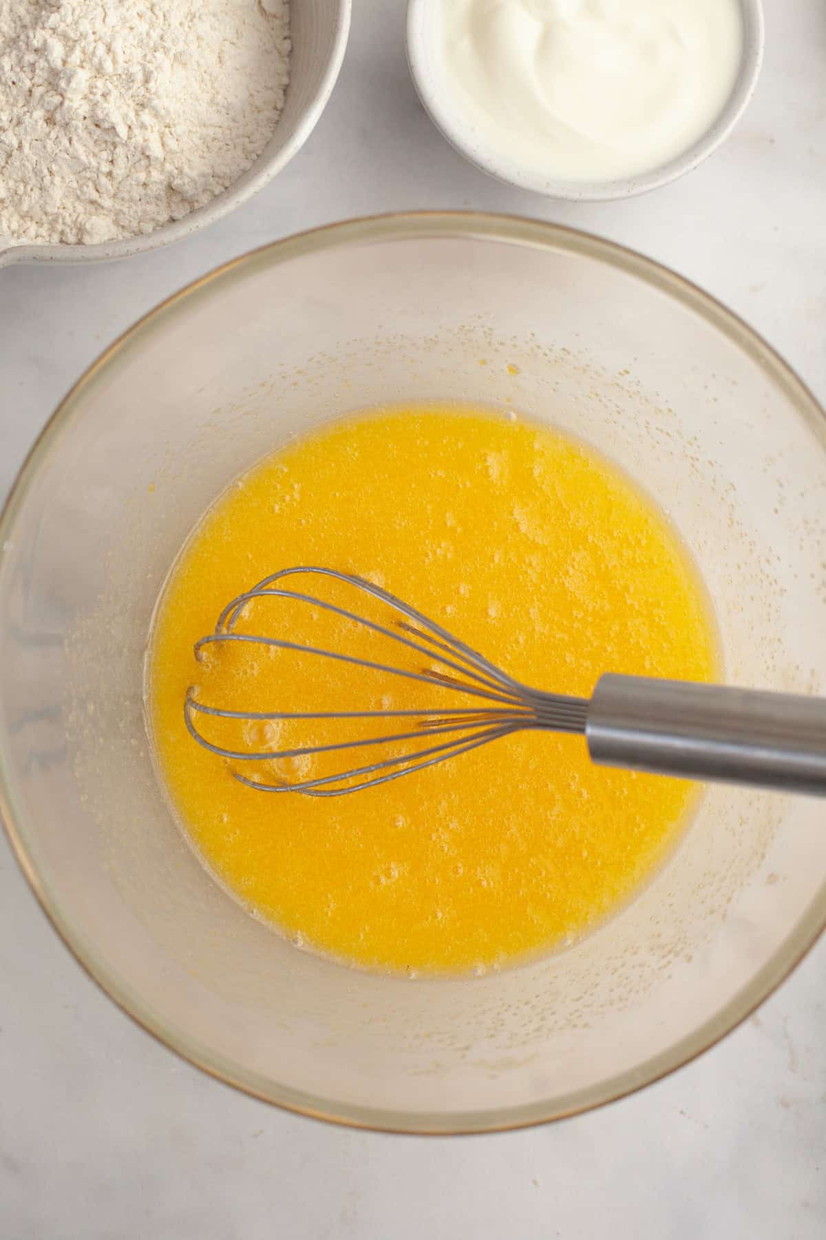 Melted butter in a glass bowl with a whisk.
