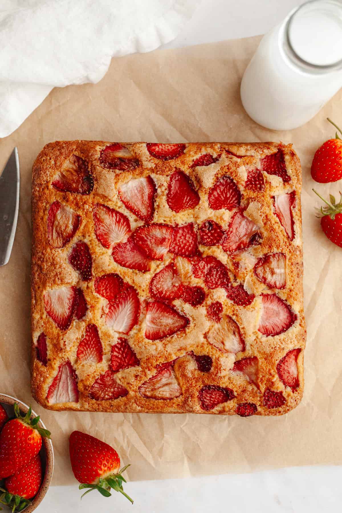 A square strawberry snack cake on parchment paper.