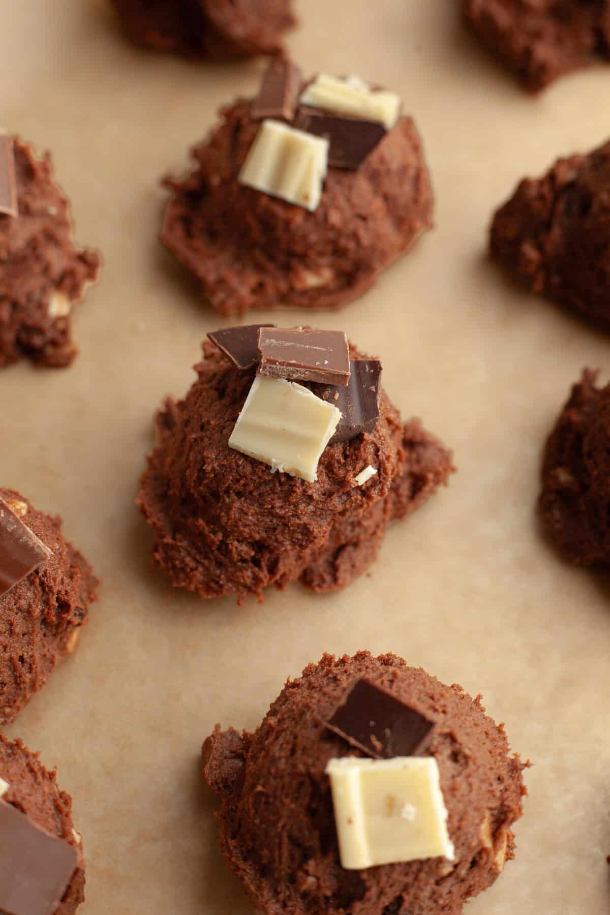 Chocolate chunk cookie dough balls on parchment paper.