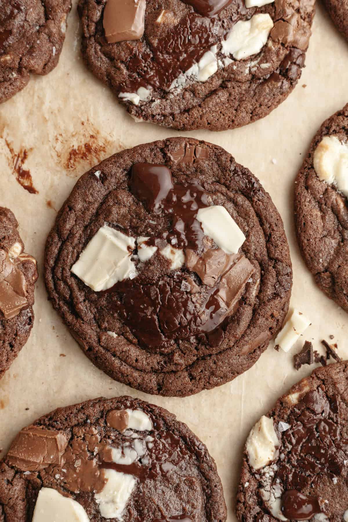 A close up of triple chocolate chunk cookies on parchment paper.