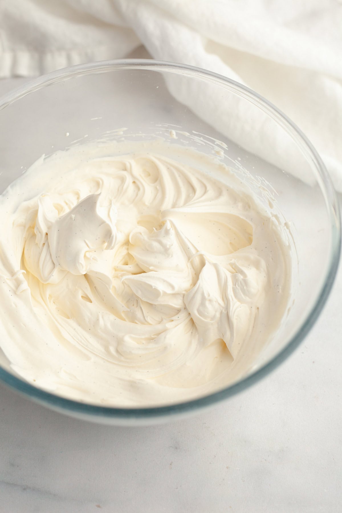 A glass bowl with vanilla bean whipped cream.