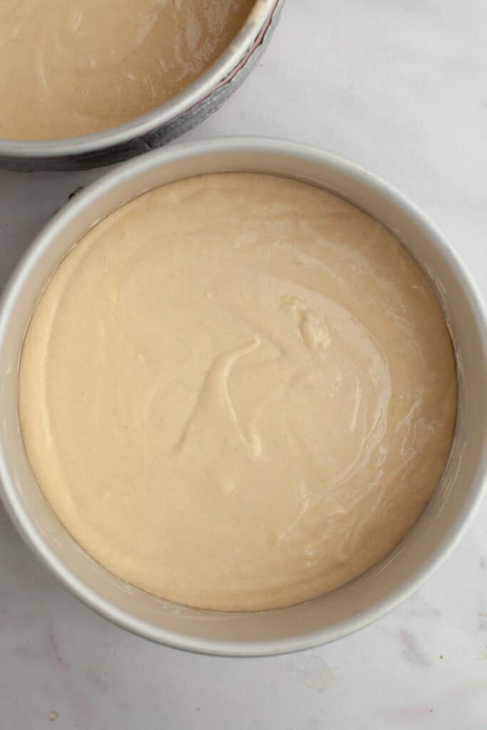 Two round cake pans with unbaked vanilla cake batter.