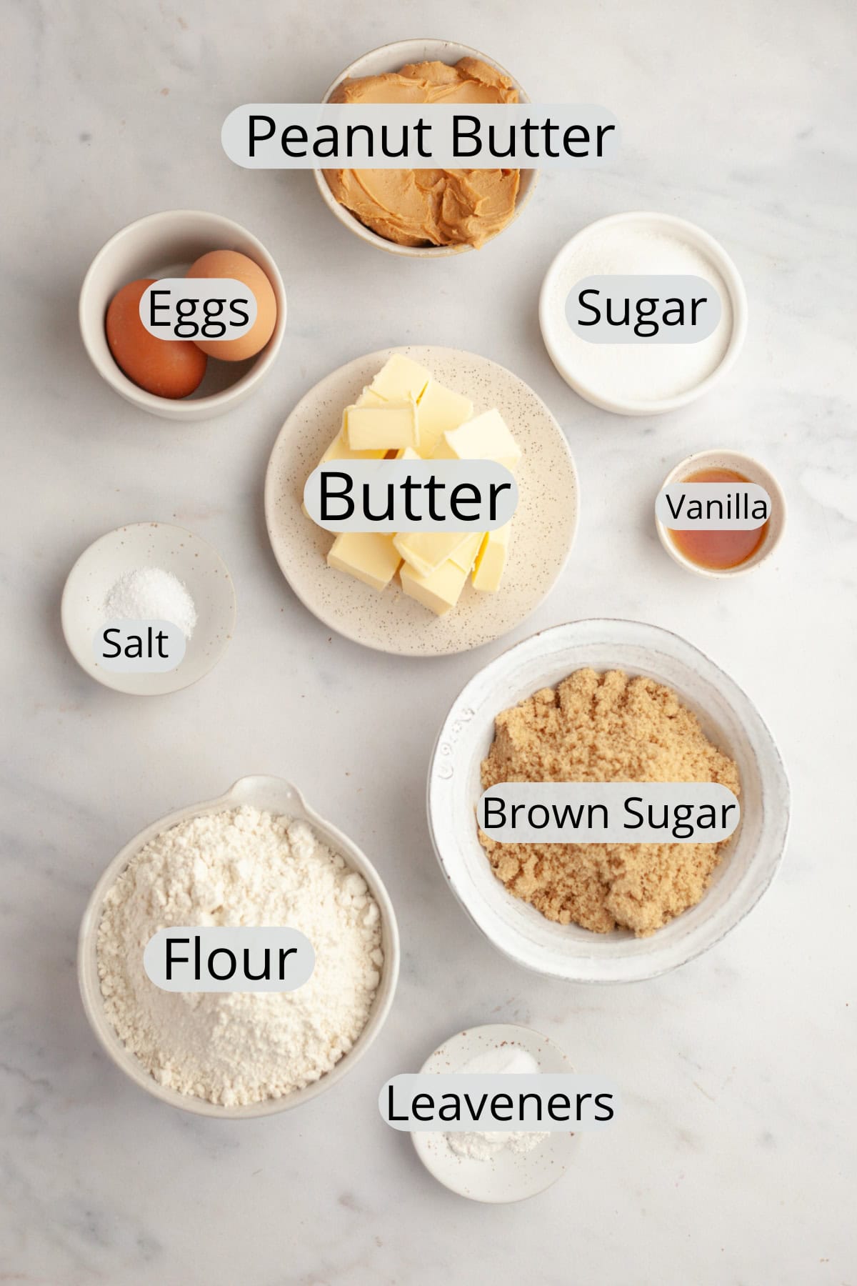 All the ingredients needed to make browned butter peanut butter cookies, weighed out into small bowls.