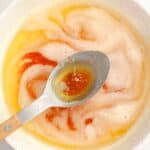 A bowl filled with browned butter and a spoon with some of the brown butter in it.