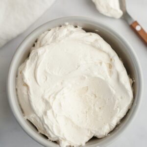 A light grey bowl filled with mascarpone whipped cream frosting.