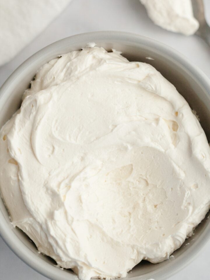 A light grey bowl filled with mascarpone whipped cream frosting.