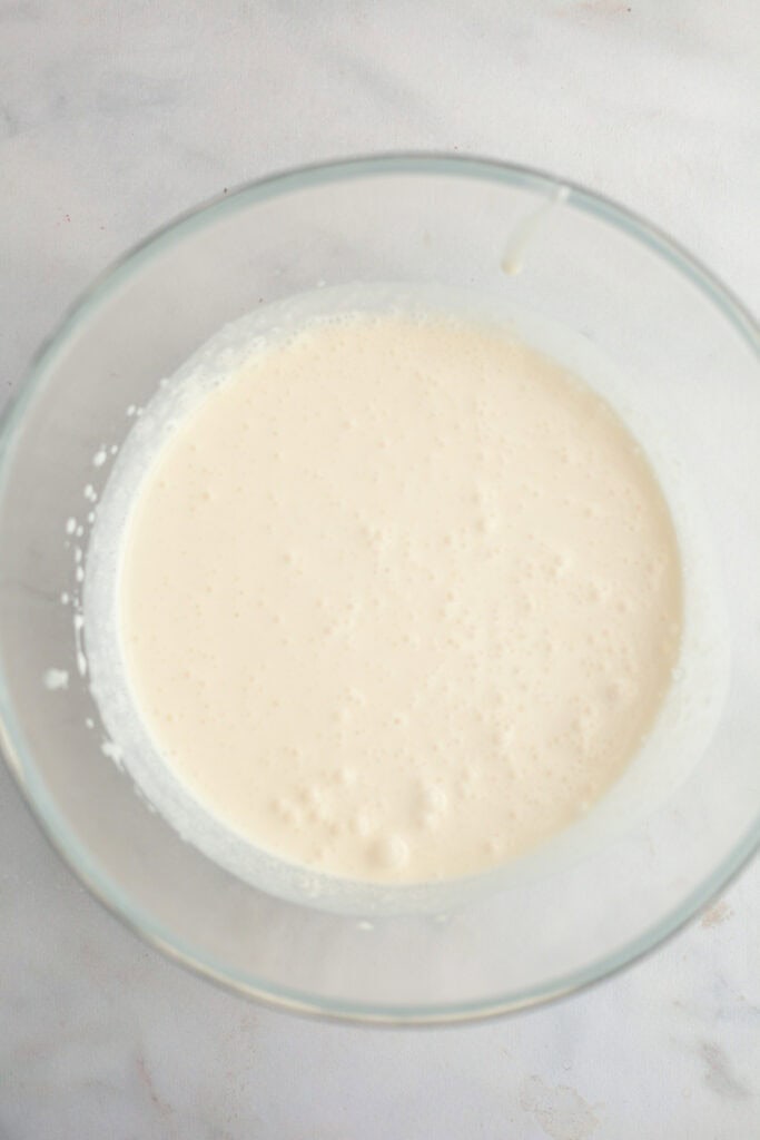 A large glass bowl with heavy cream in it.