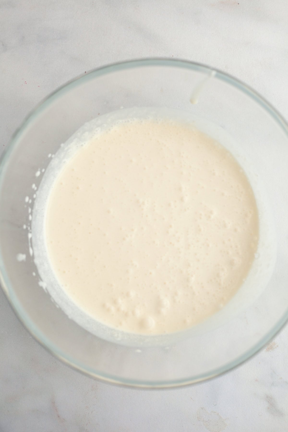 A large glass bowl with heavy cream in it.
