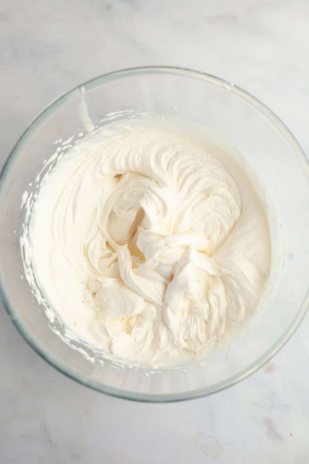 A large glass bowl filled with mascarpone whipped cream frosting.