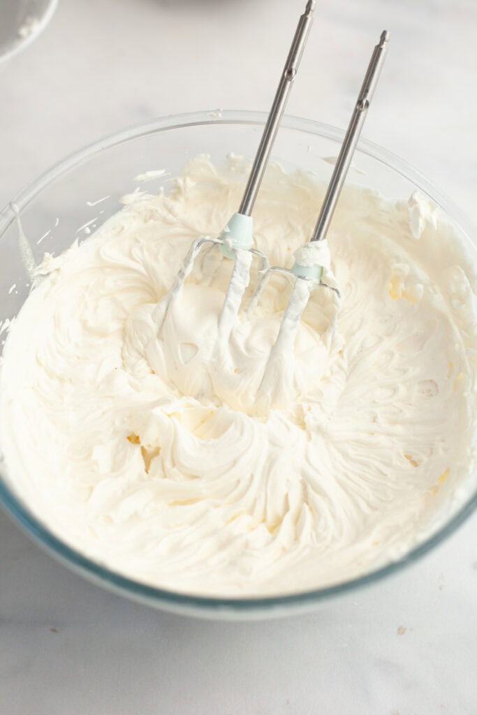 A large glass bowl filled with mascarpone whipped cream frosting.
