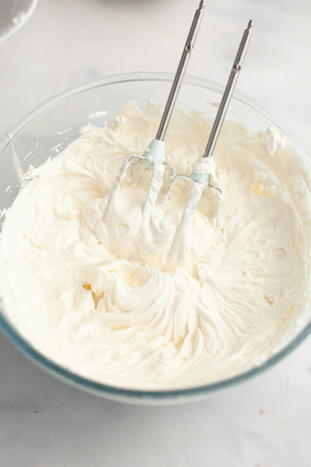 A large glass bowl filled with mascarpone whipped cream frosting.