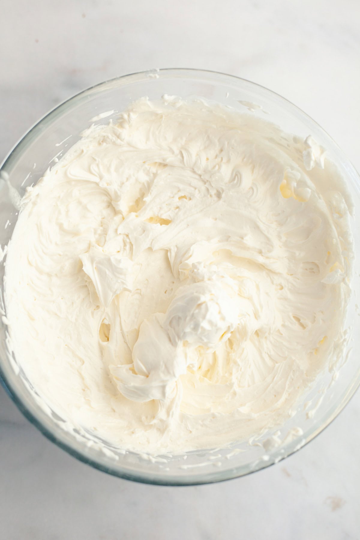 A large glass bowl filled with mascarpone whipped cream frosting.