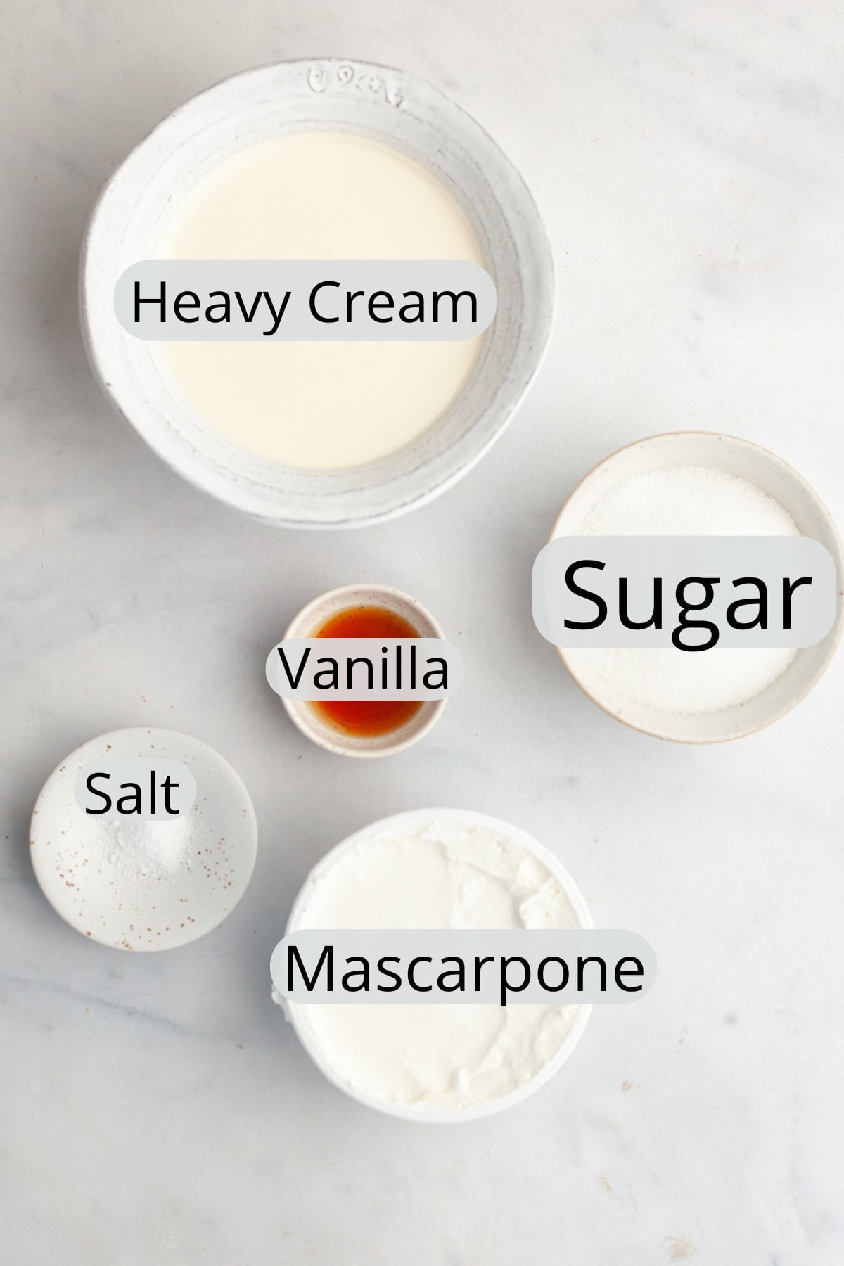 All the ingredients needed to make mascarpone whipped cream frosting, weighed out into small bowls.