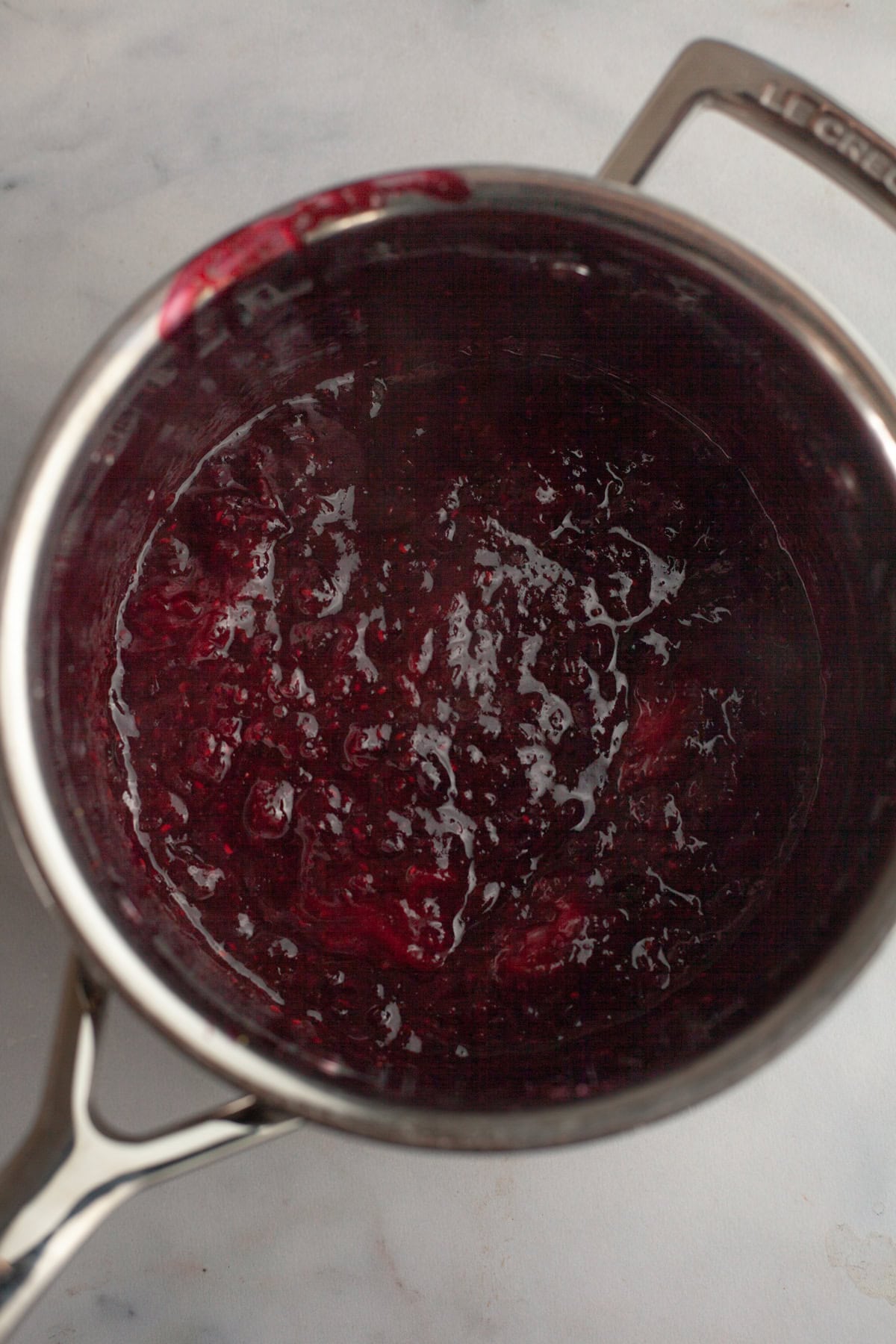 Mixed berry compote in a silver saucepan.