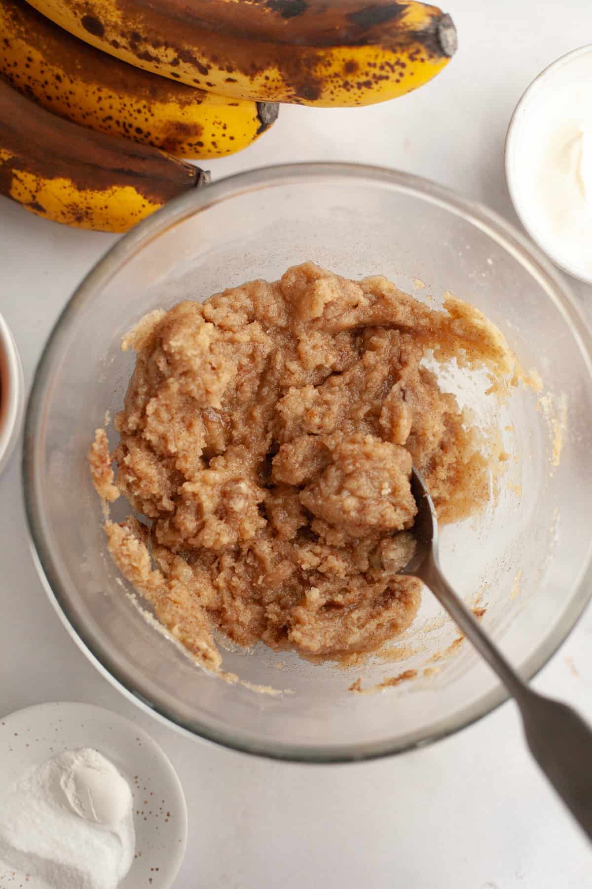 A glass bowl with a spoon and streusel topping in it.