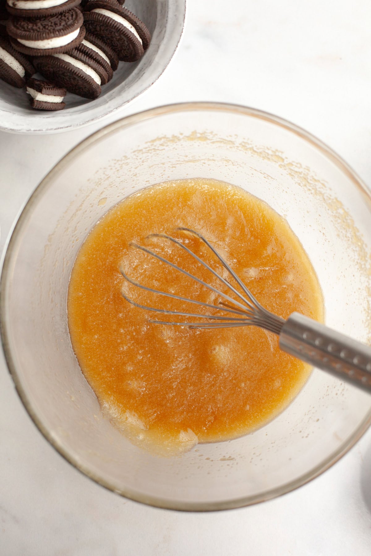 Melted butter and sugar in a glass bowl with a whisk.