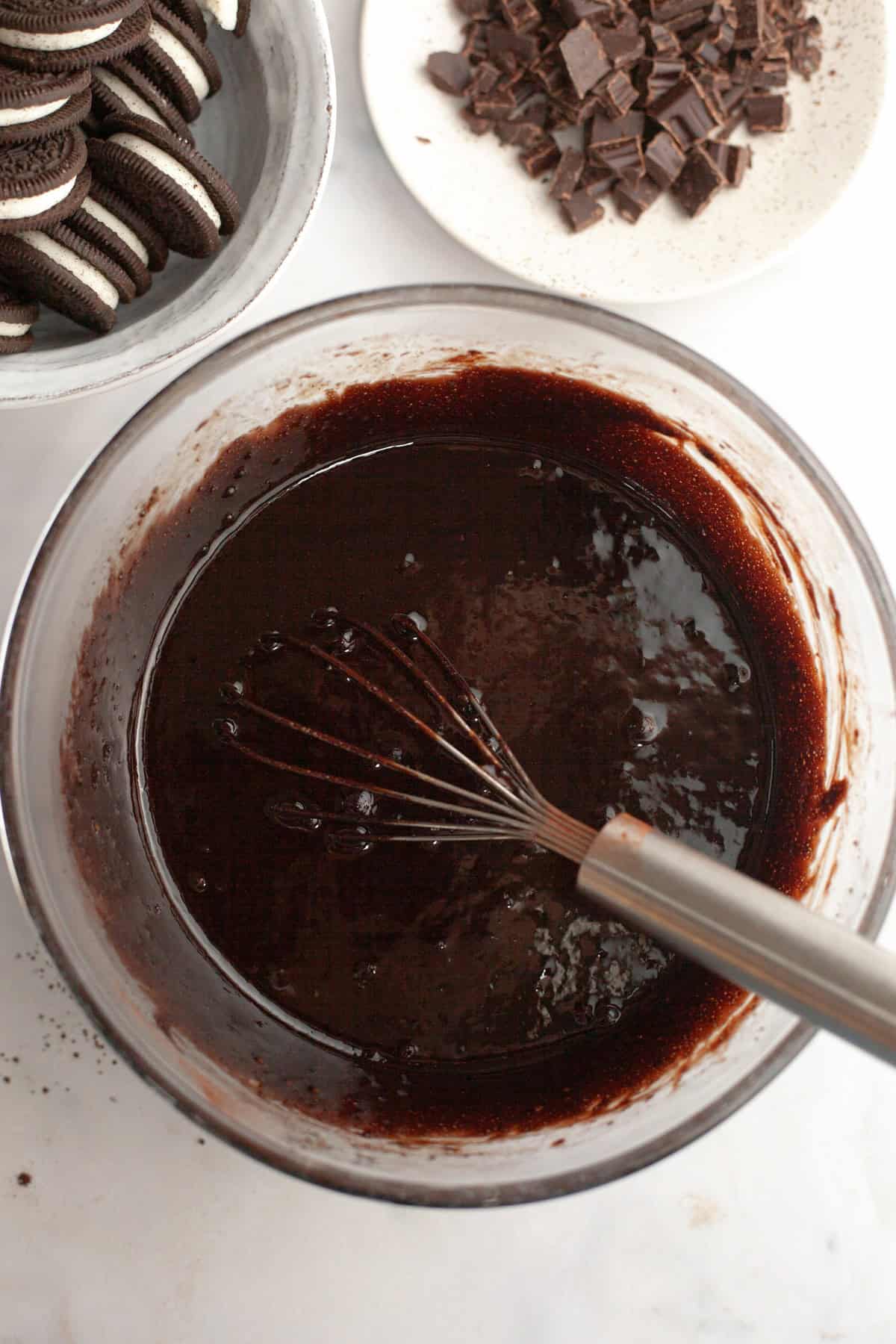 A large glass bowl with a whisk and brownie batter.