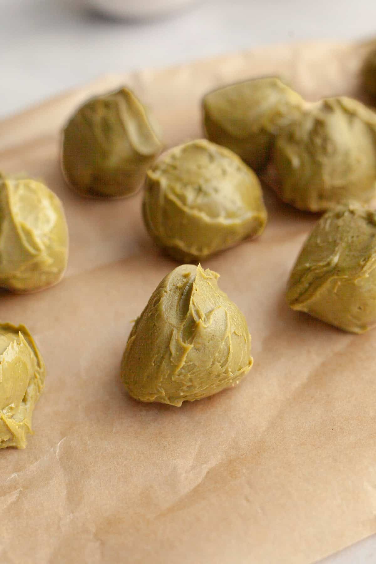 Balls of pistachio spread on parchment paper.