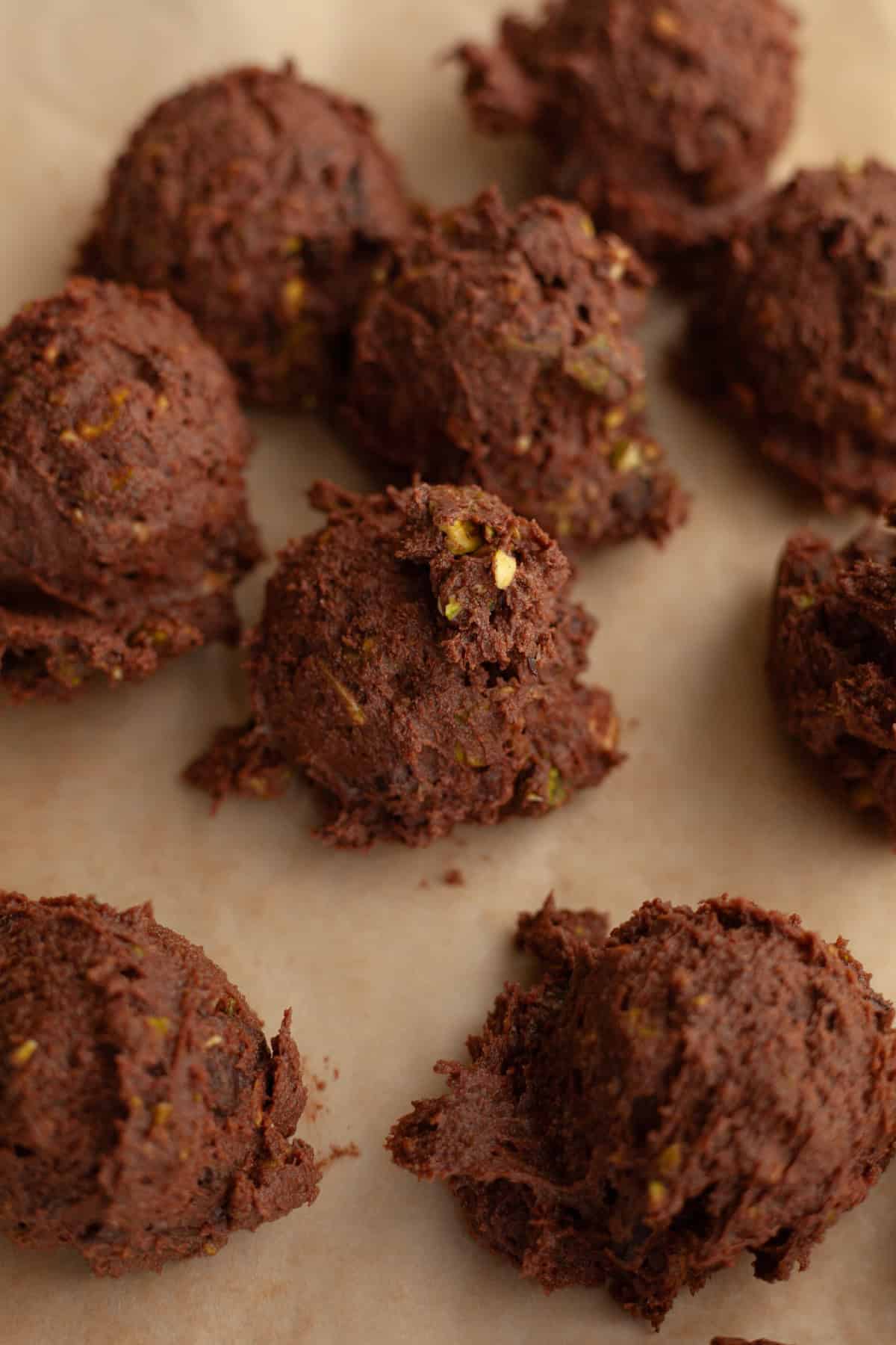 Chocolate pistachio cookie dough balls on parchment paper.
