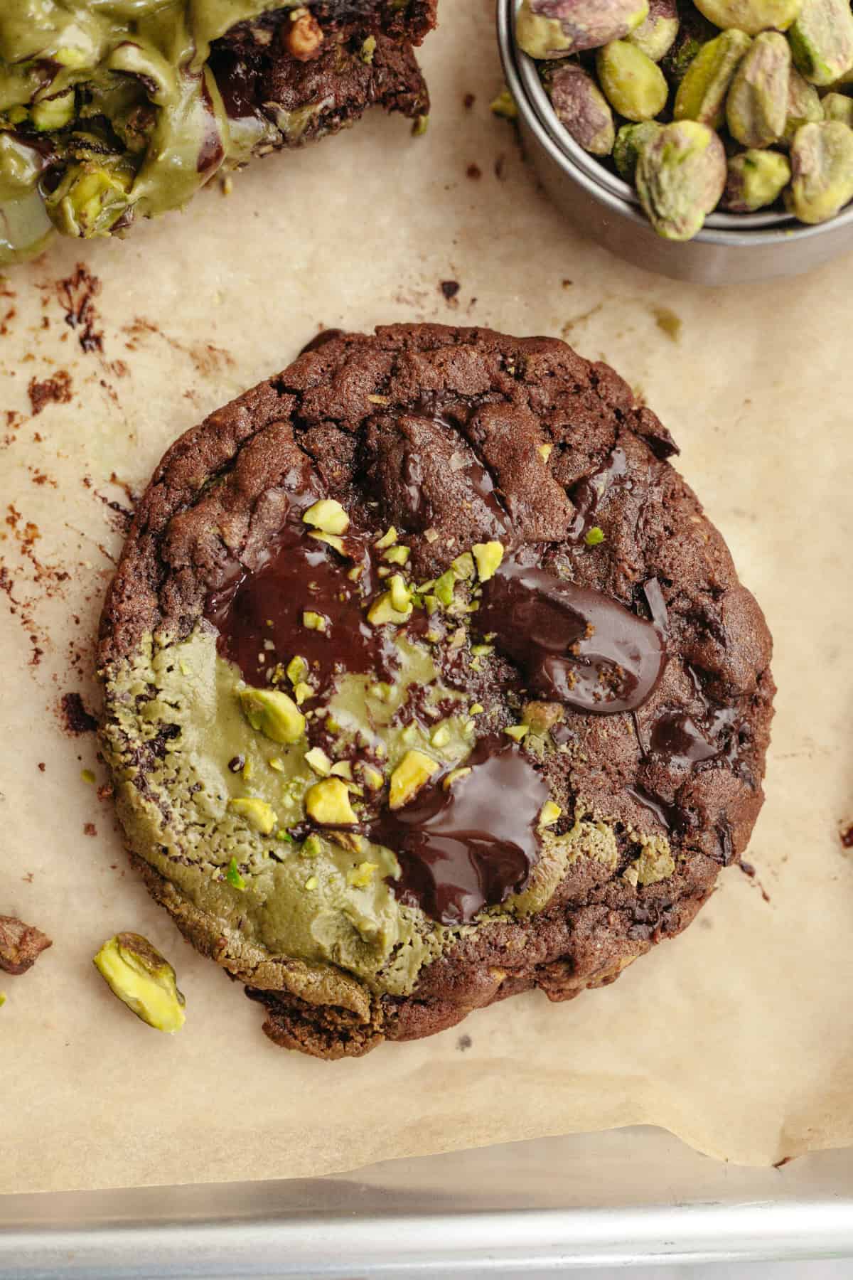 A close up of a pistachio chocolate cookie on parchment paper.