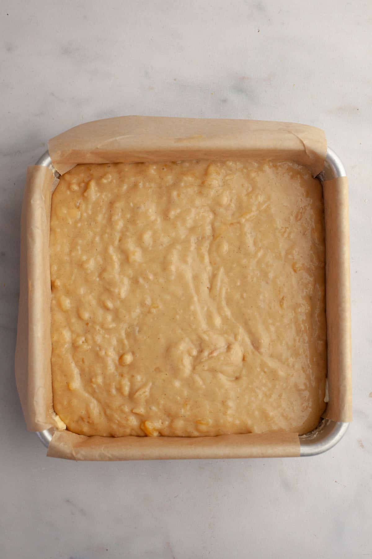 Unbaked banana cake in a square baking pan.