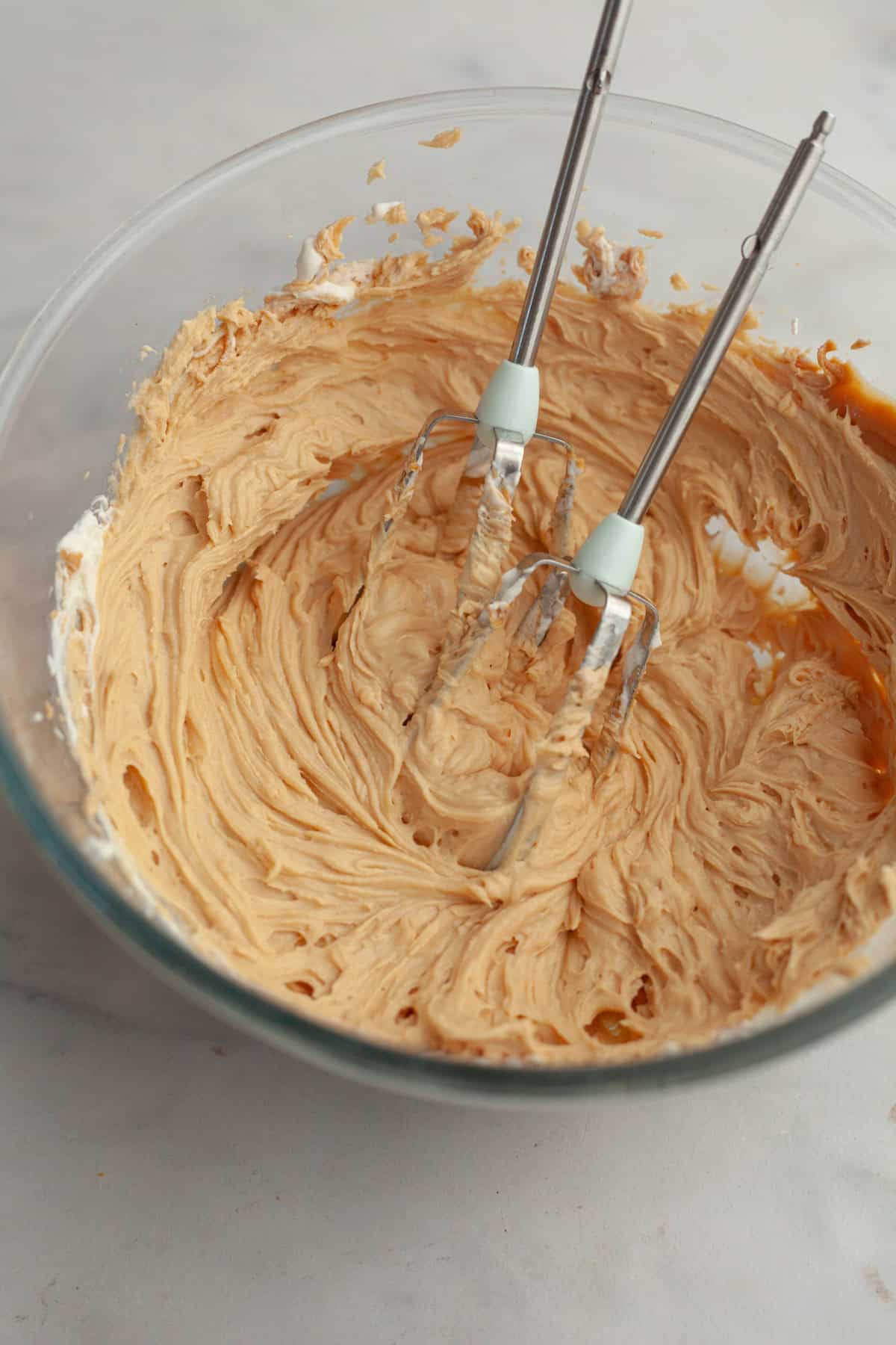 Peanut butter frosting in a glass bowl.