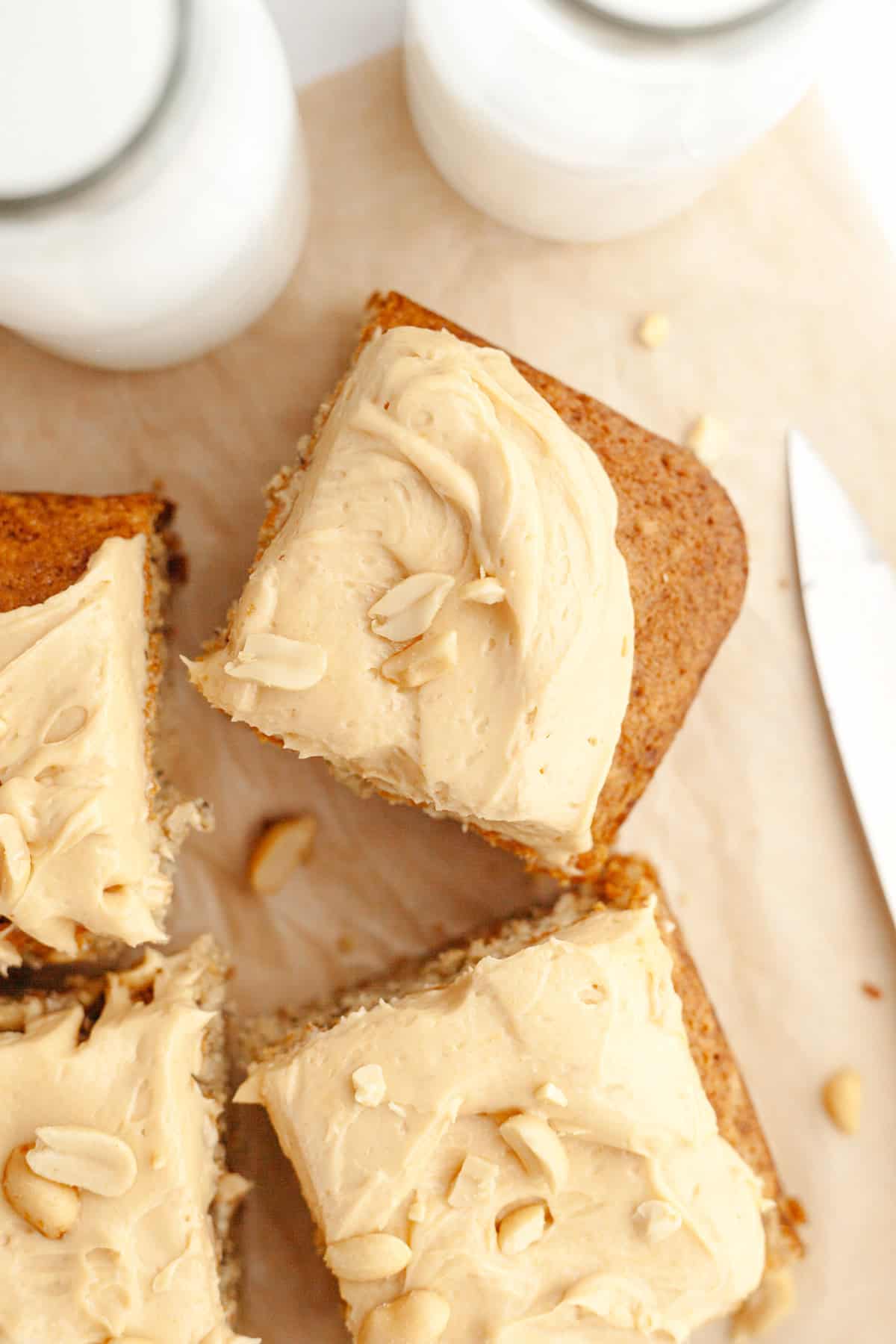Square slices of banana cake topped with peanut butter frosting and salted peanuts.