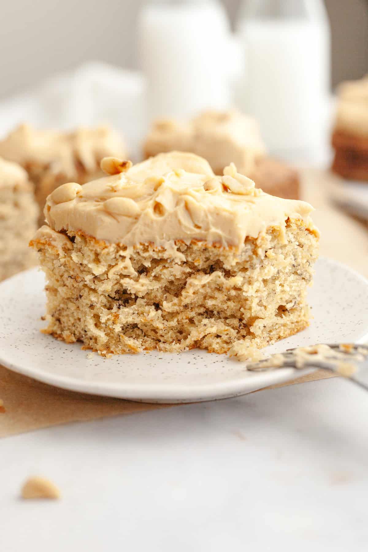 A slice of banana cake with peanut butter frosting on a small plate.