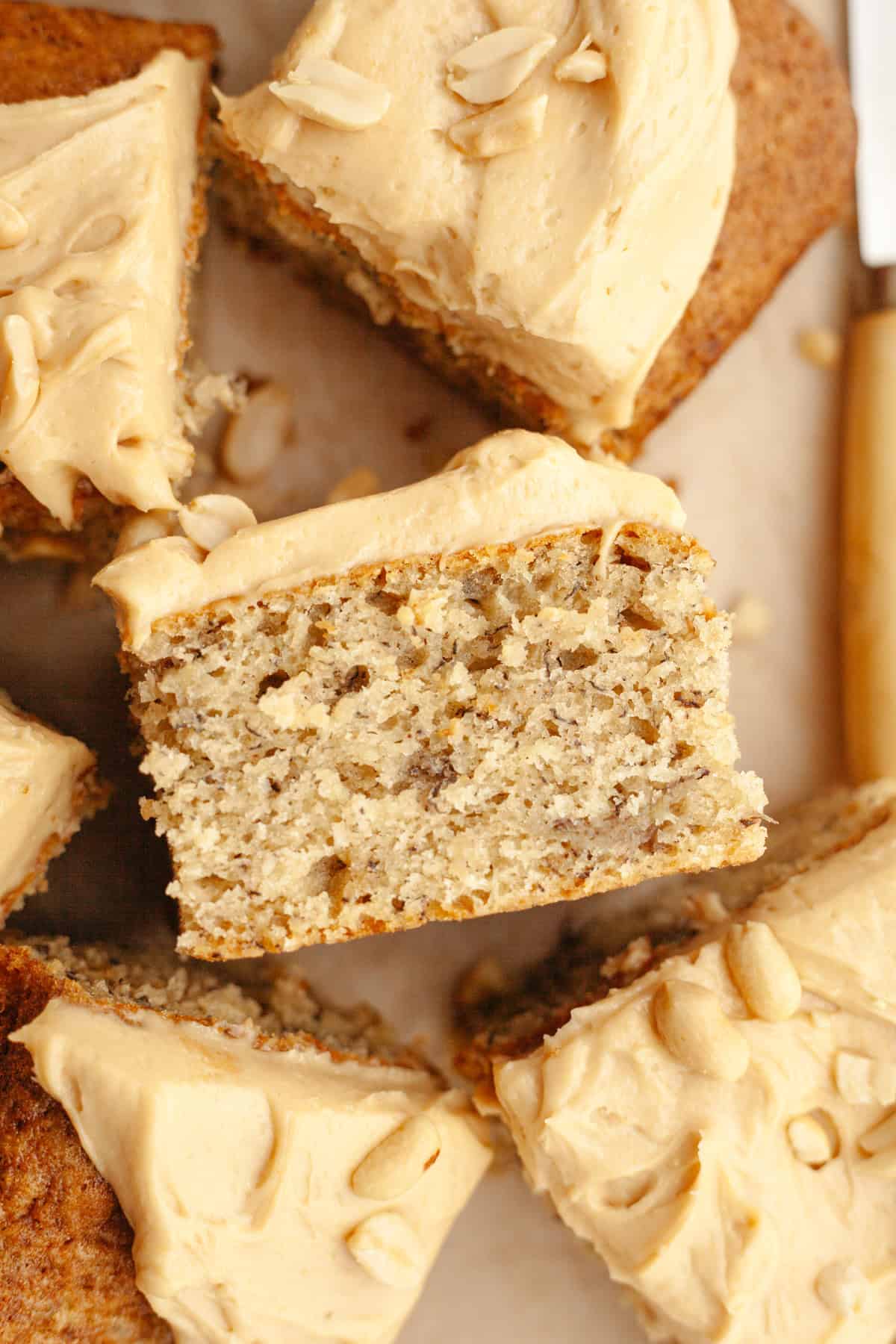 Square slices of banana cake topped with peanut butter frosting and salted peanuts.