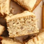 A close up of a slice of banana cake with peanut butter frosting, on it's side.
