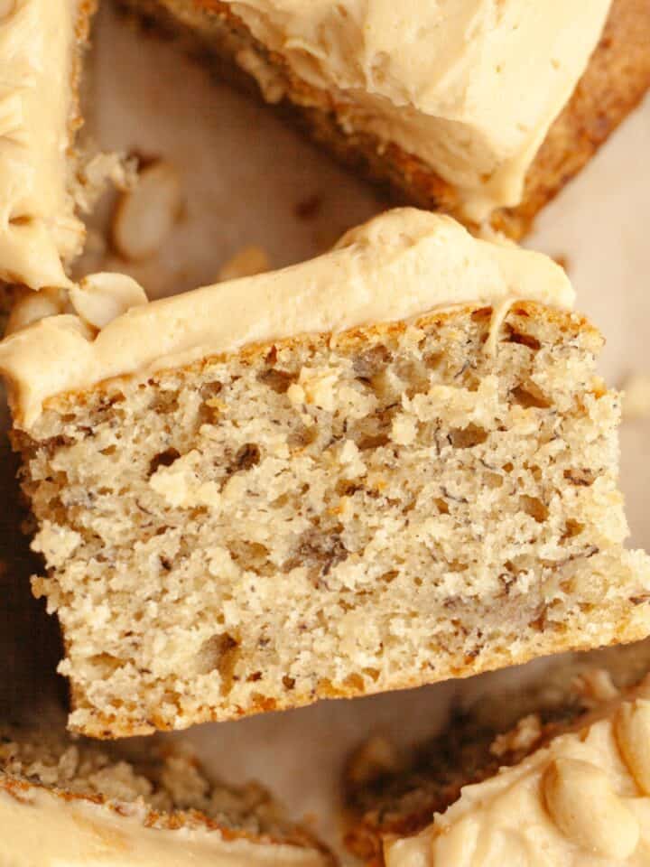 A close up of a slice of banana cake with peanut butter frosting, on it's side.