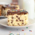 A slice of chocolate chip sheet cake with chocolate frosting on a small plate.
