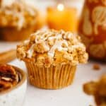 A close up of a pumpkin pecan muffin with a white glaze.