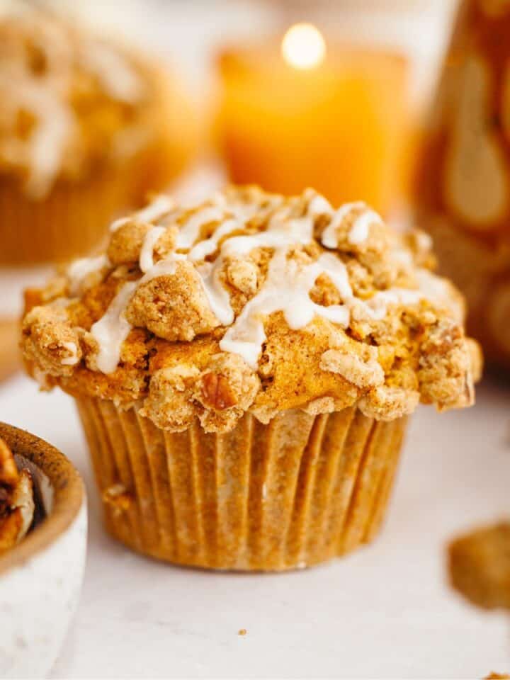 A close up of a pumpkin pecan muffin with a white glaze.