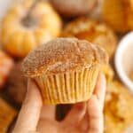 A hand holding a pumpkin sour cream muffin covered in sugar.